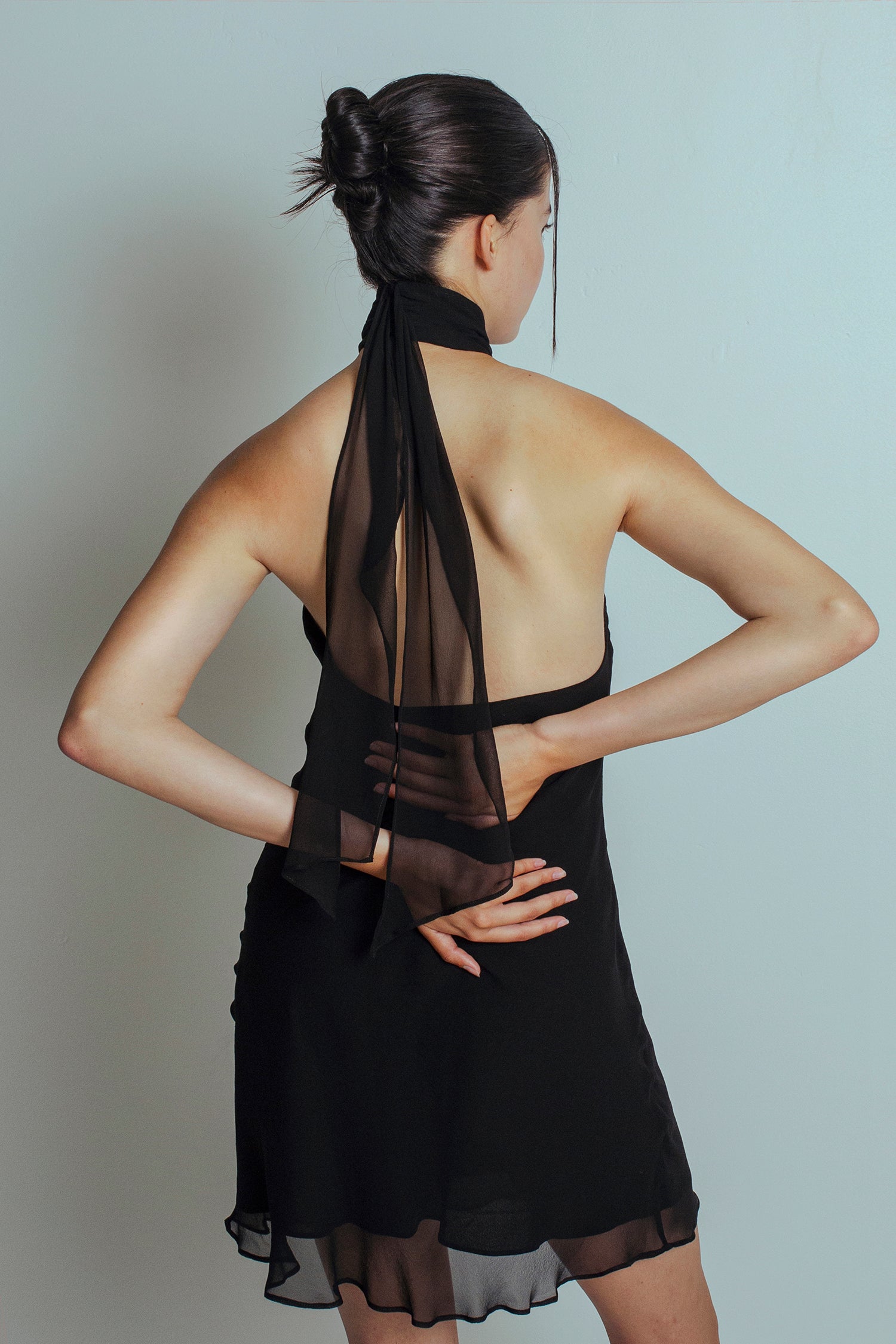 Back view of Black mini length dress with bare back and flowing ties at the neckband