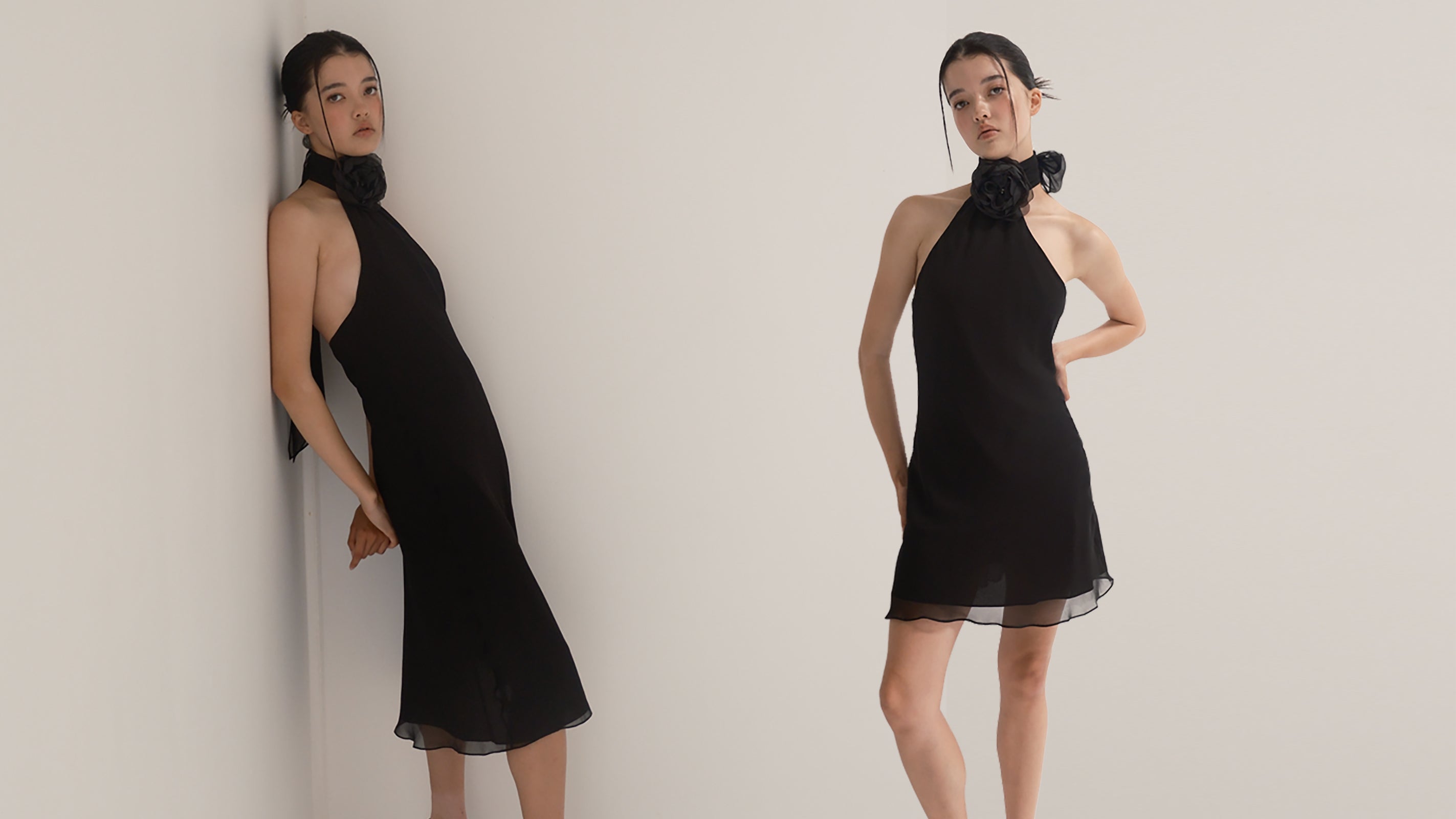 Image of two models wearing a Black midi and mini length dress with an asymmetrical neckline and a flower brooch at the neckband